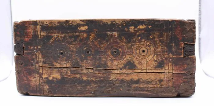 Weathered carved wooden block with circular patterns, showcasing old treasures discovered by passionate antique lovers.