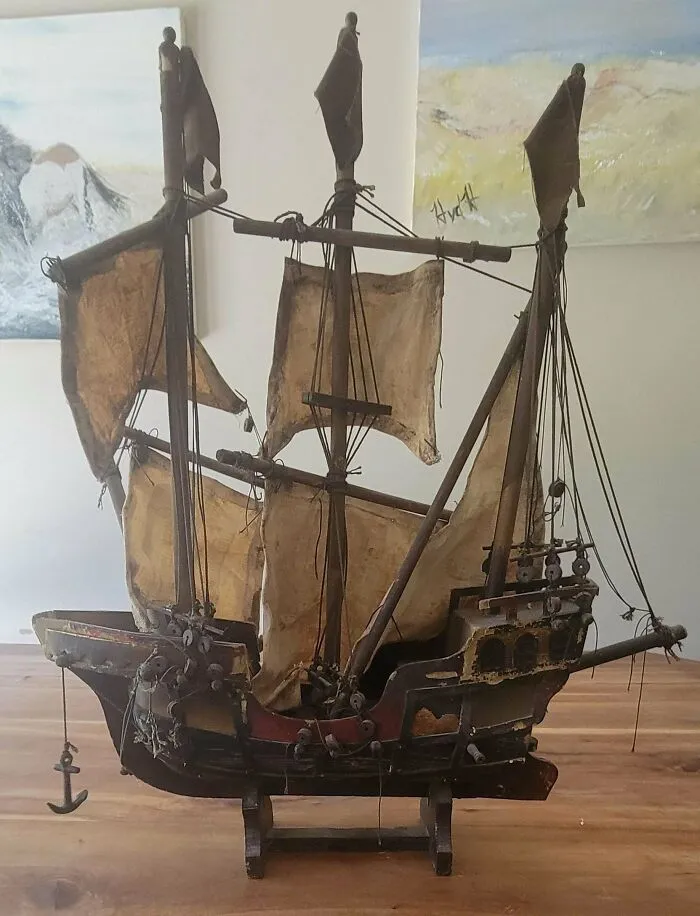 A detailed vintage model ship made of wood and fabric sitting on a table, representing amazing old treasures.