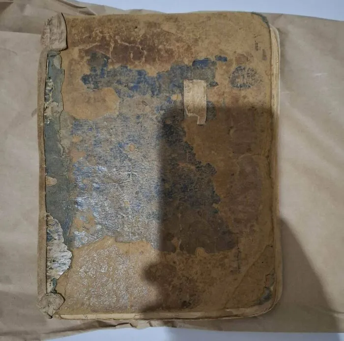 Extremely worn antique book with a weathered cover, a rare old treasure discovered by a collector.