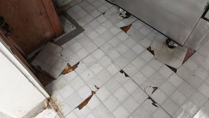 Questionable DIY projects featuring broken flooring vinyl tiles poorly fitted around a kitchen area.