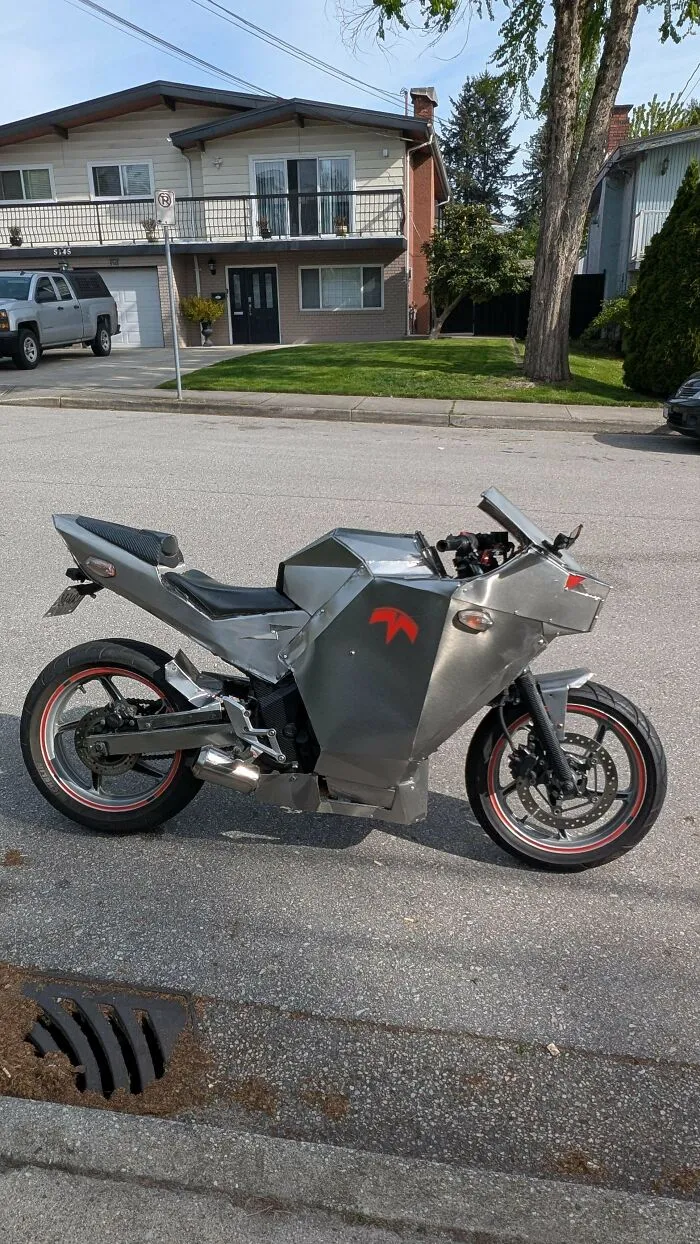 A custom metal motorcycle body modification showcased in a suburban street as a DIY project.