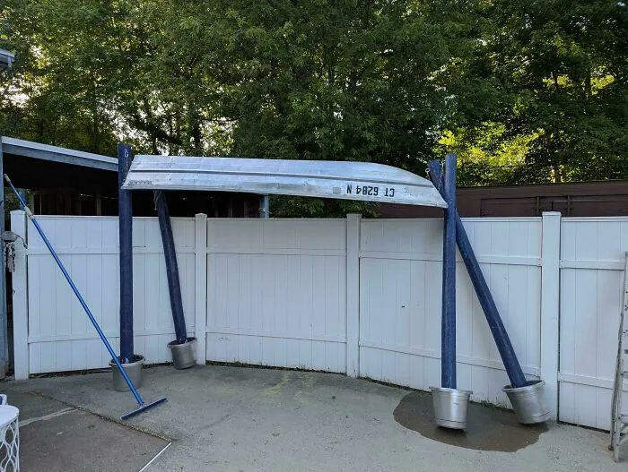 An upside-down boat used as an outdoor canopy structure, demonstrating questionable DIY projects.