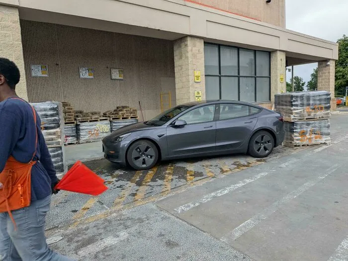 A dark grey Tesla parked in a loading zone, a common sight reported by homedepot employees