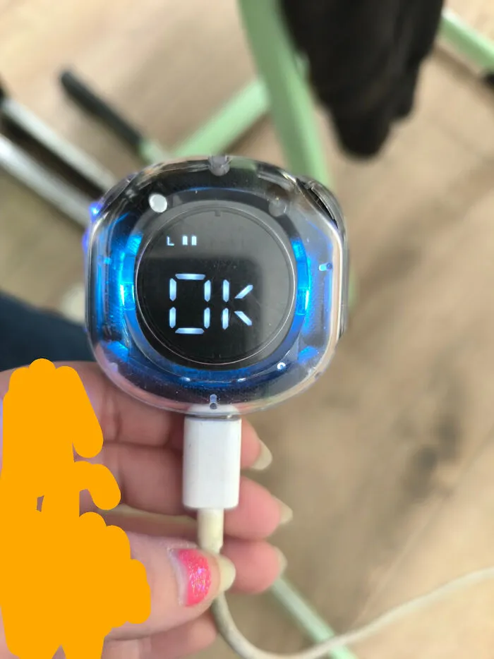 A hand holding a small digital device displaying OK with blue light, a pic from the Not Interesting community.