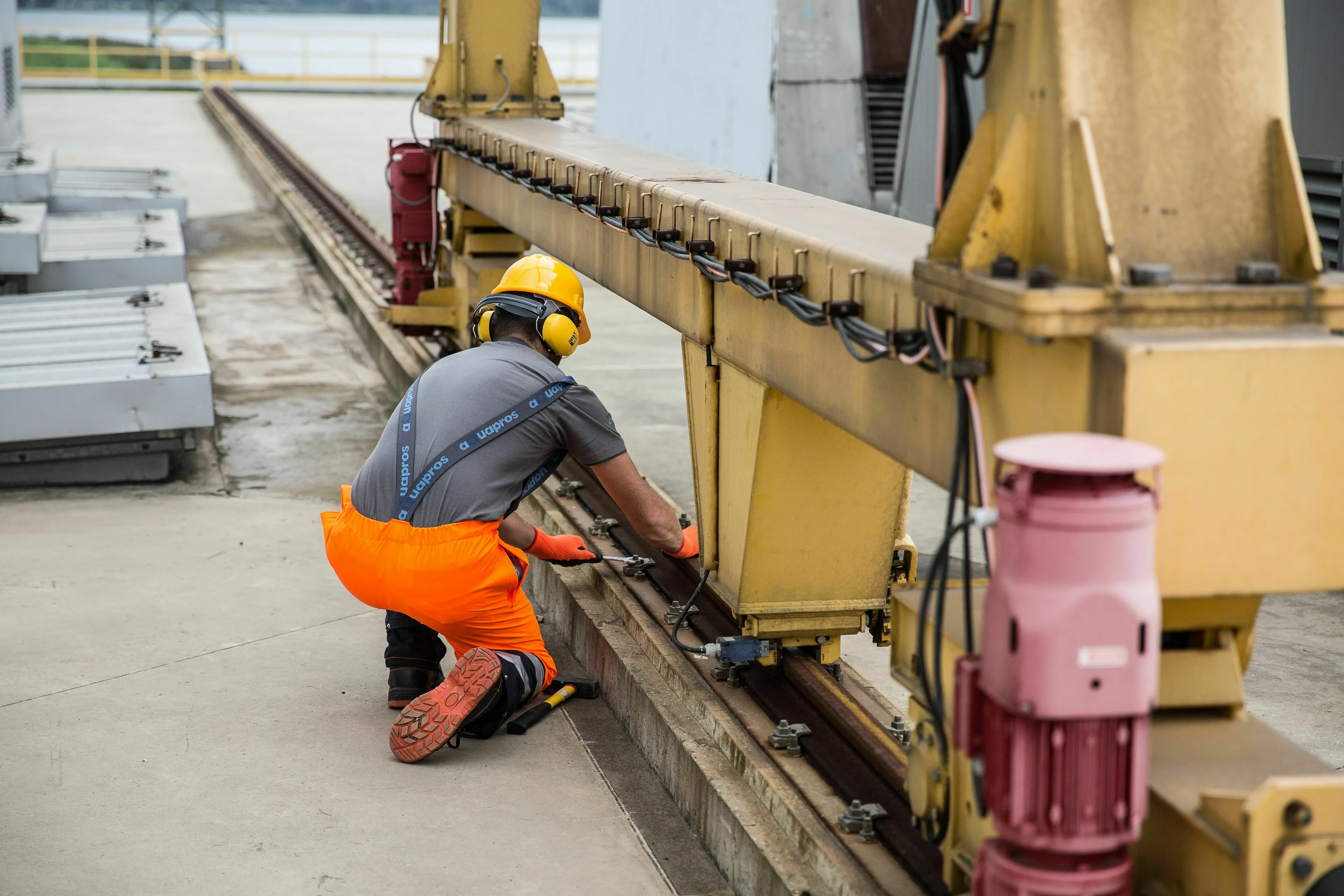 A worker in a hard hat and safety gear inspects machinery, crucial for understanding how is this word spelled in complex industrial terms.