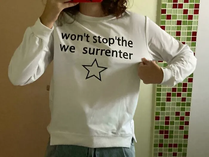 White long-sleeve shirt with the phrase 'won't stop the we surrenter' and a star, highlighting bad clothing designs.