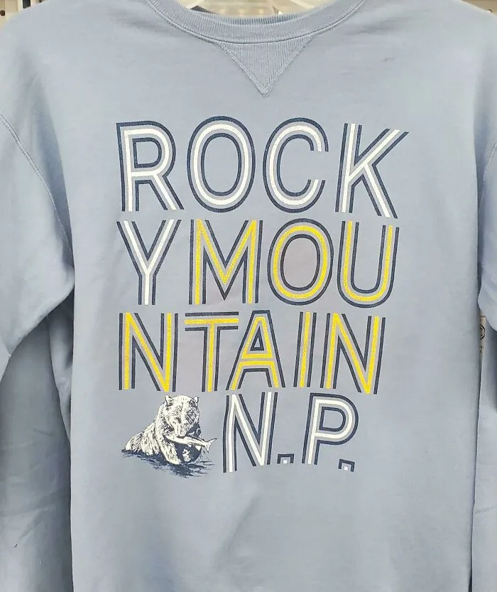 Light blue sweatshirt with ROCKY MOUNTAIN N.P. text and a bear, showcasing bad clothing designs.
