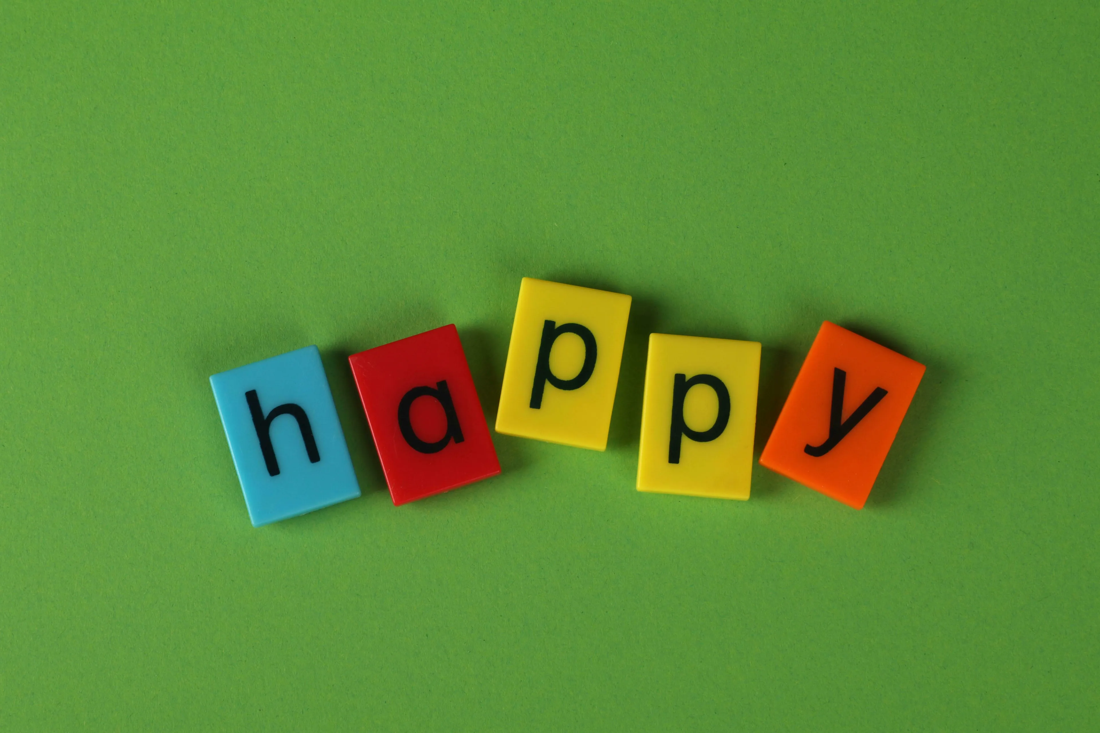 Magnetic letters spelling HAPPY on a green background. Experience joy and find your happy place.