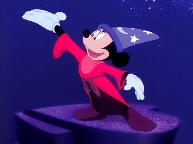 Mickey Mouse as the Sorcerer's Apprentice from Fantasia, wearing a red robe and blue hat, against a starry night sky.