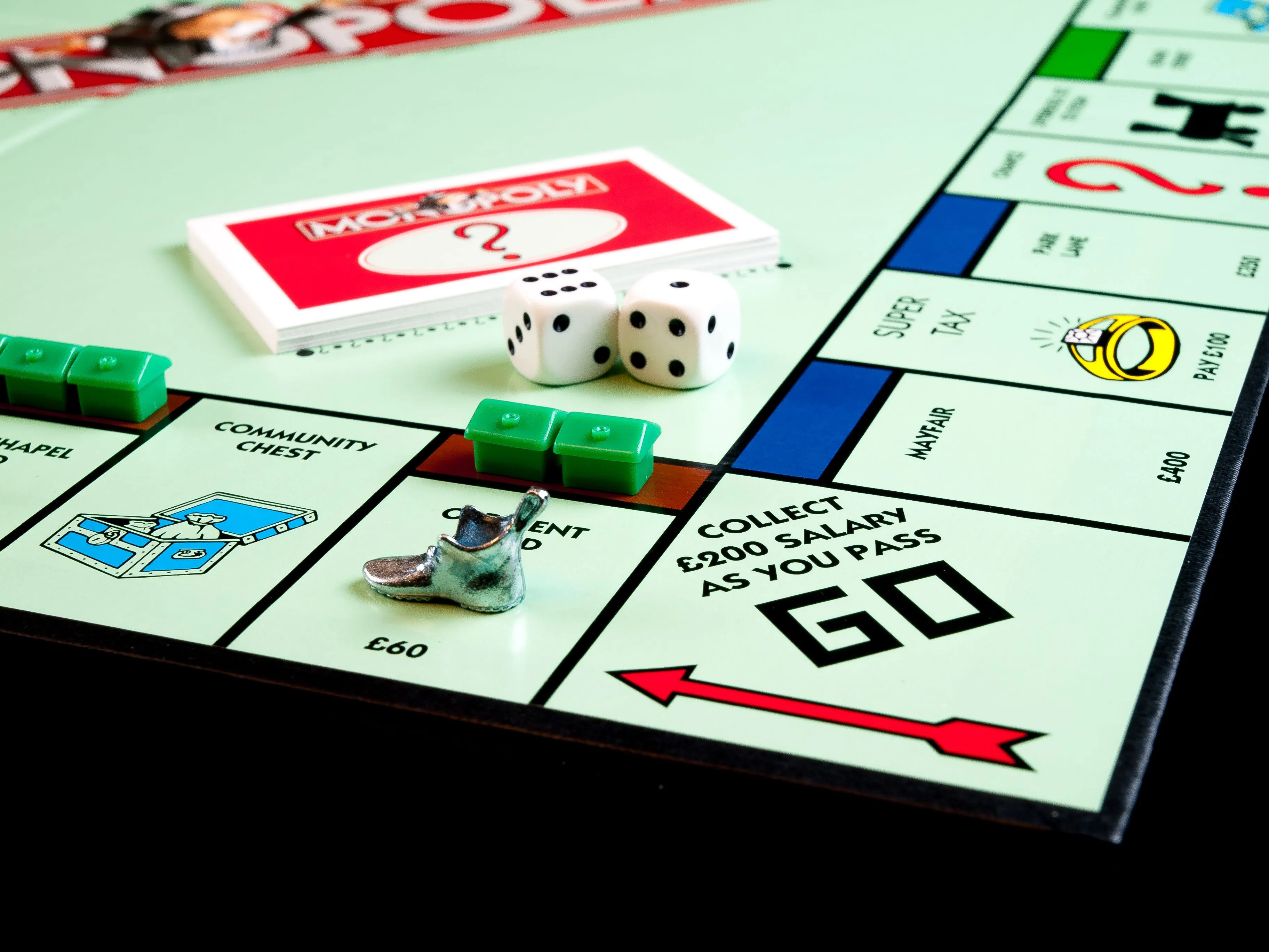 A Monopoly board game setup, with dice, game pieces, and property cards visible. Pick a board game, Monopoly.