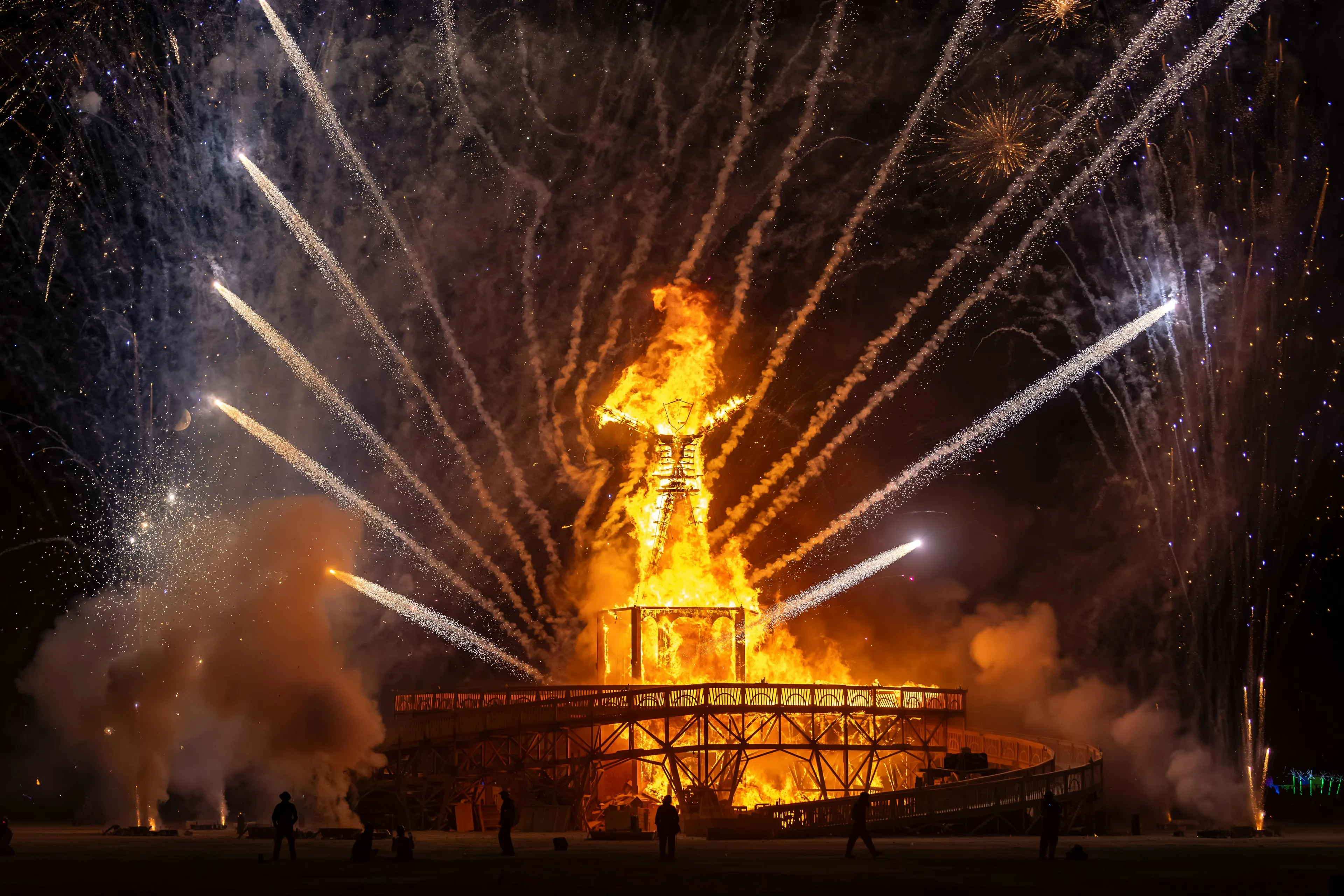 A blazing effigy, surrounded by fireworks at the Burning Man festival, lighting up the night sky. Famous festival around the world.
