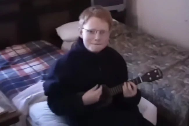 Young Ed Sheeran playing ukulele, bringing joy. His early music for the song Photograph, reflecting on joy.