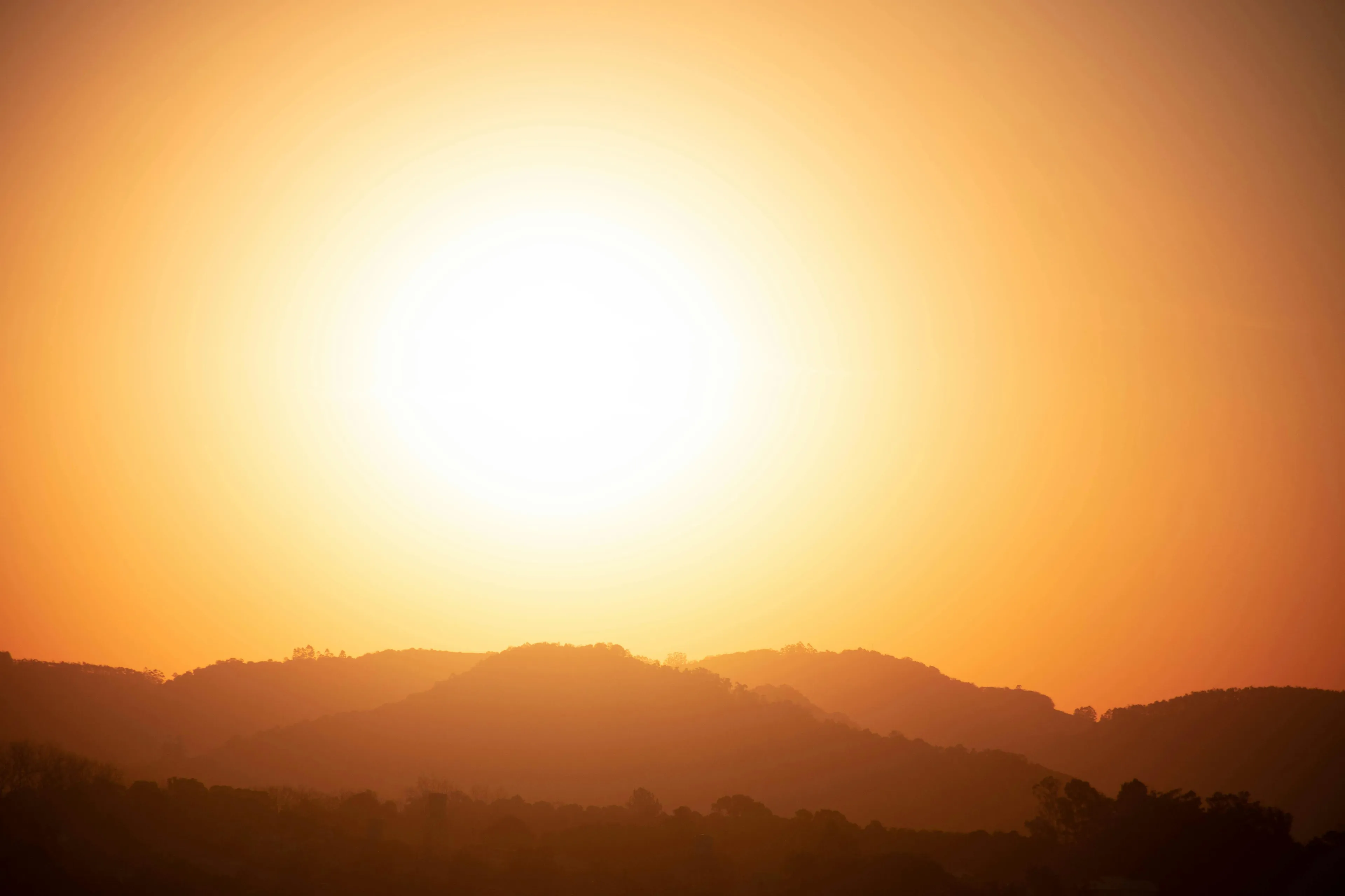 Golden hour light illuminates silhouetted mountains, creating a warm, vibrant type of light over the landscape.