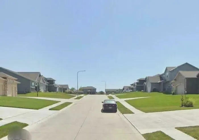 Suburban street with identical houses and a single car parked on road