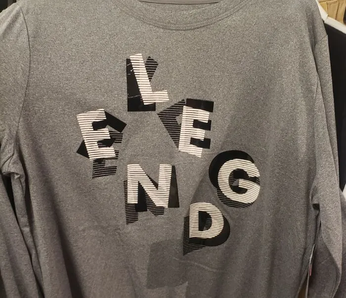 A grey long-sleeved shirt with the word LEGEND stylized awkwardly, part of a collection of bad clothing designs.