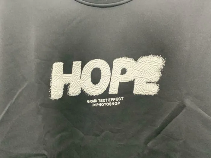 A dark gray clothing design with the word 'Hope' in white and 'Grain text effect in Photoshop' below it, representing bad clothing designs.