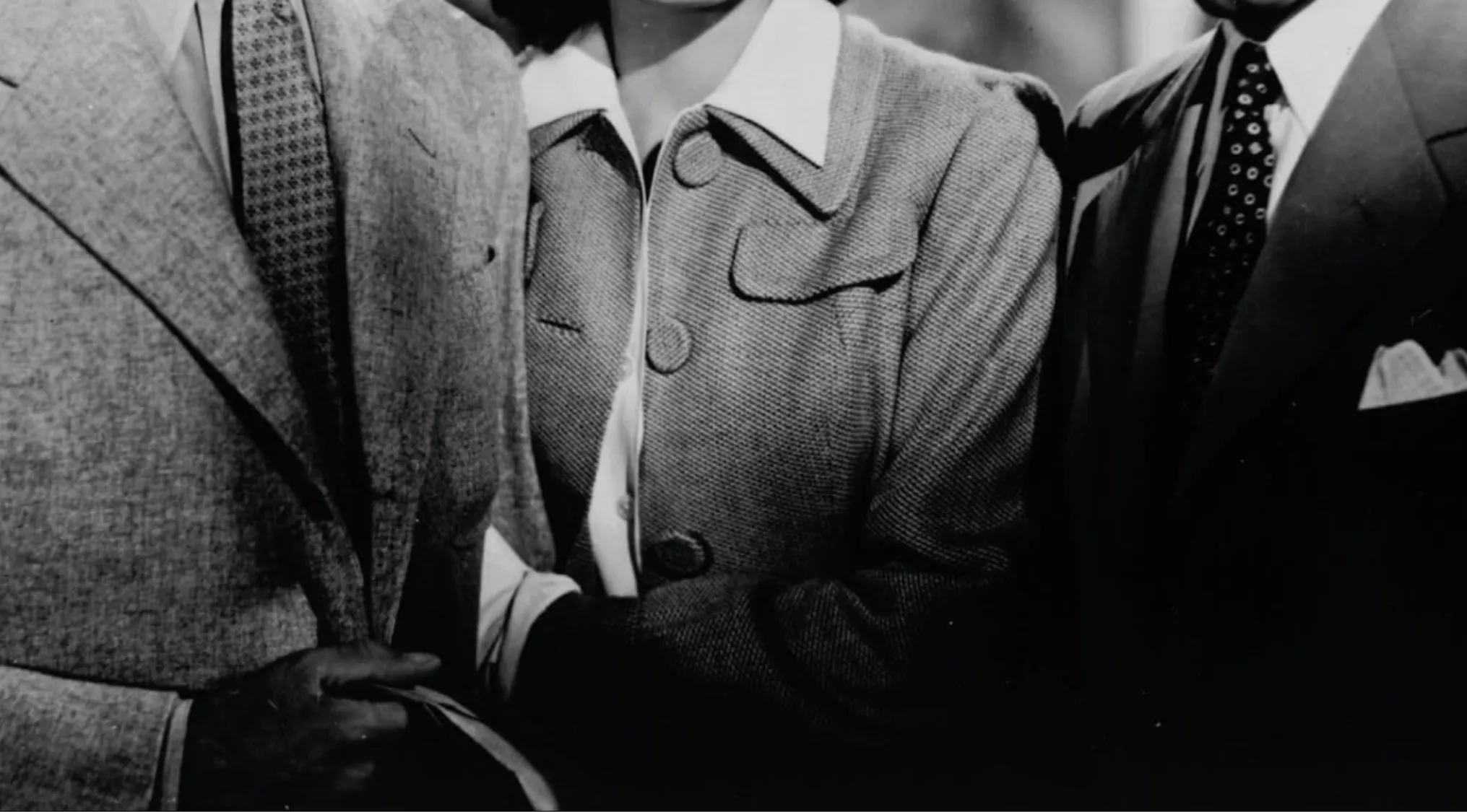 Black and white photo of three people, focused on their torsos and iconic outfits. Old Hollywood glamour.