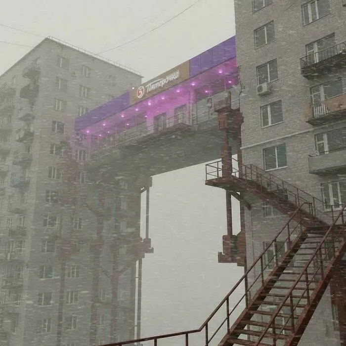 Snowstorm hitting buildings connected by a skybridge with purple lights urban hell