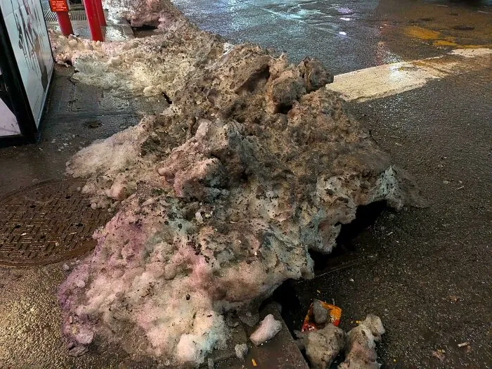 Dirty piles of melting snow on an urban street at night in urban hell conditions