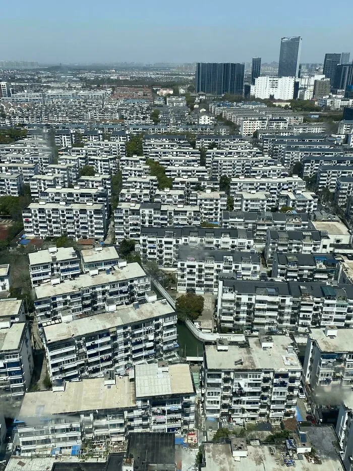 Overhead view of densely packed urban buildings with some greenery and waterways