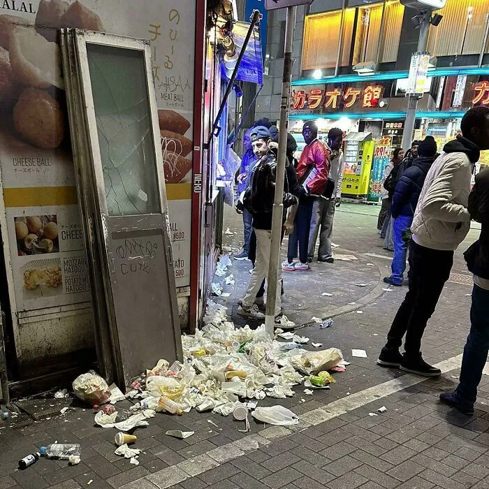 Urban hell street littered with trash and people at night