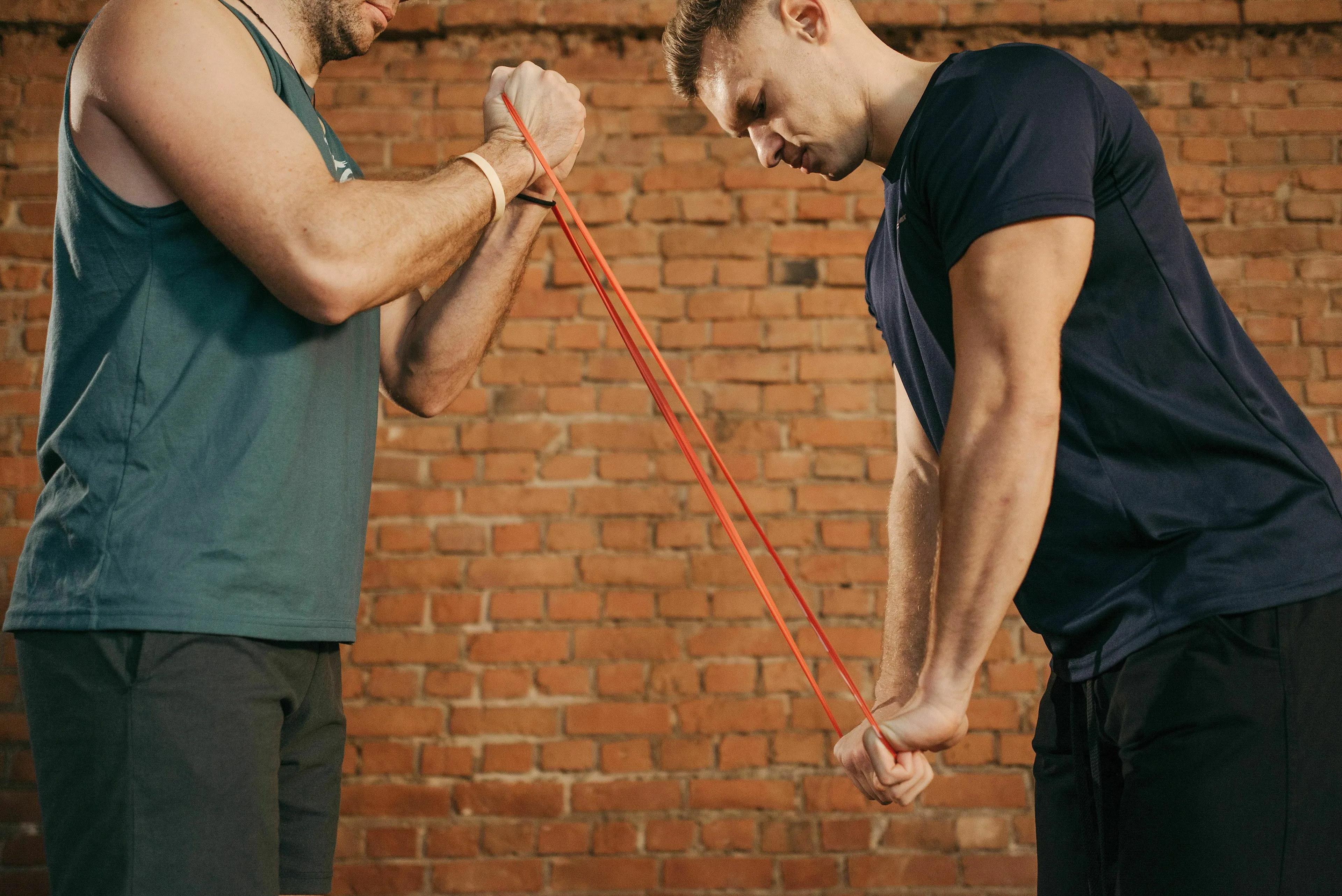 Two men using a resistance band for exercise, demonstrating potential energy, a concept from a science general knowledge quiz.