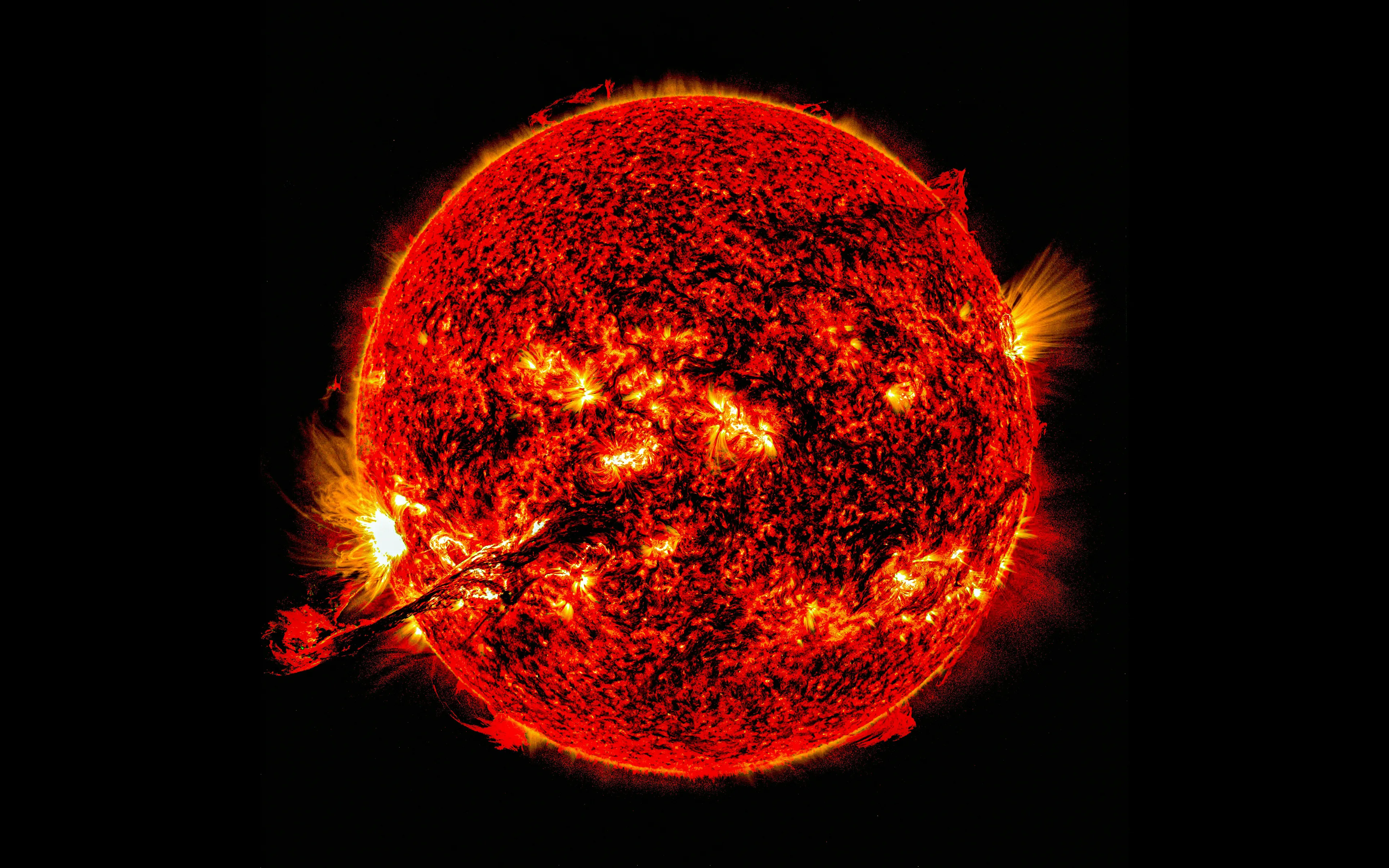 A detailed view of the Sun with fiery red and orange surface activity, featuring a large solar flare. Science general knowledge.