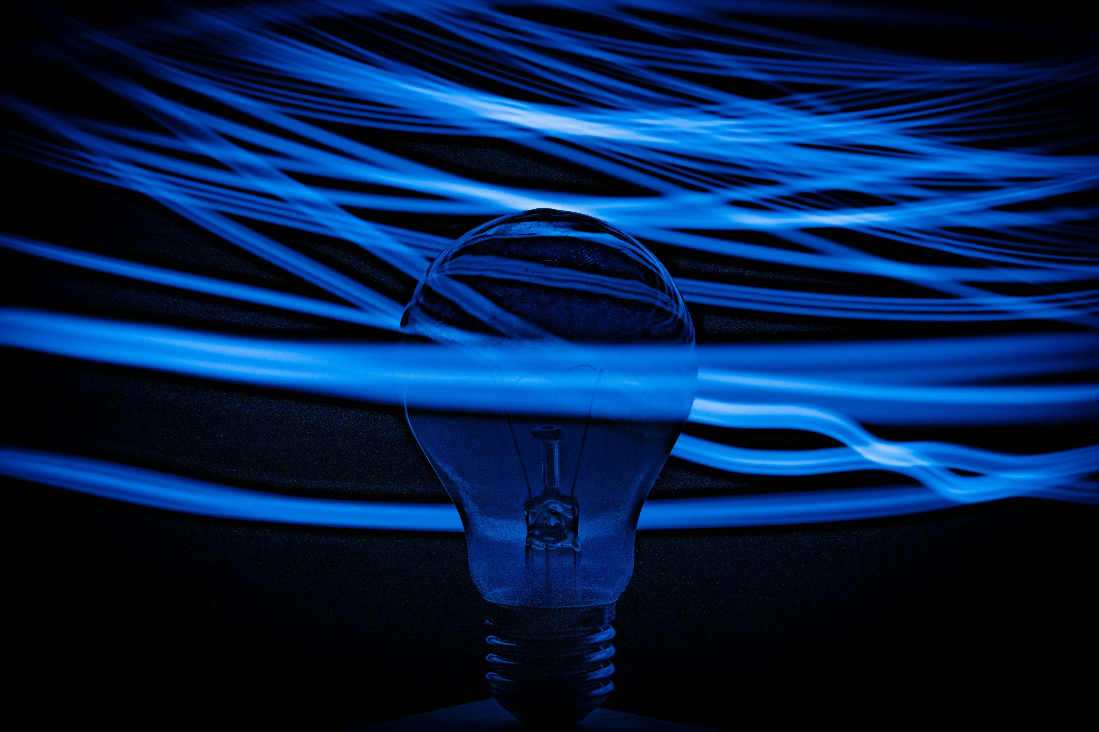 A lightbulb with blue light trails in the background, symbolizing electrical conductivity for a science general knowledge quiz.