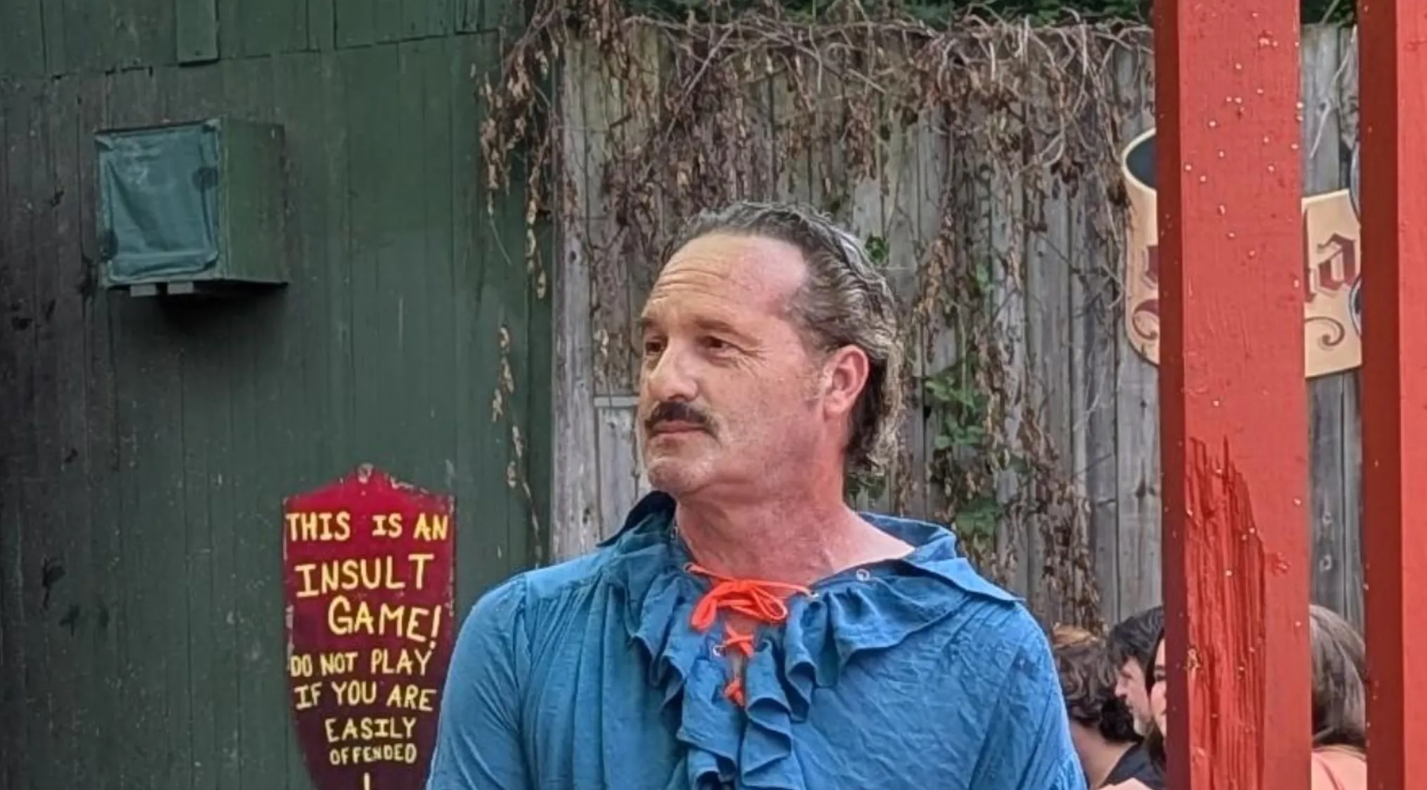 A man in a blue ruffled shirt with a mustache, looking left. Could he be a celebrity doppelganger?