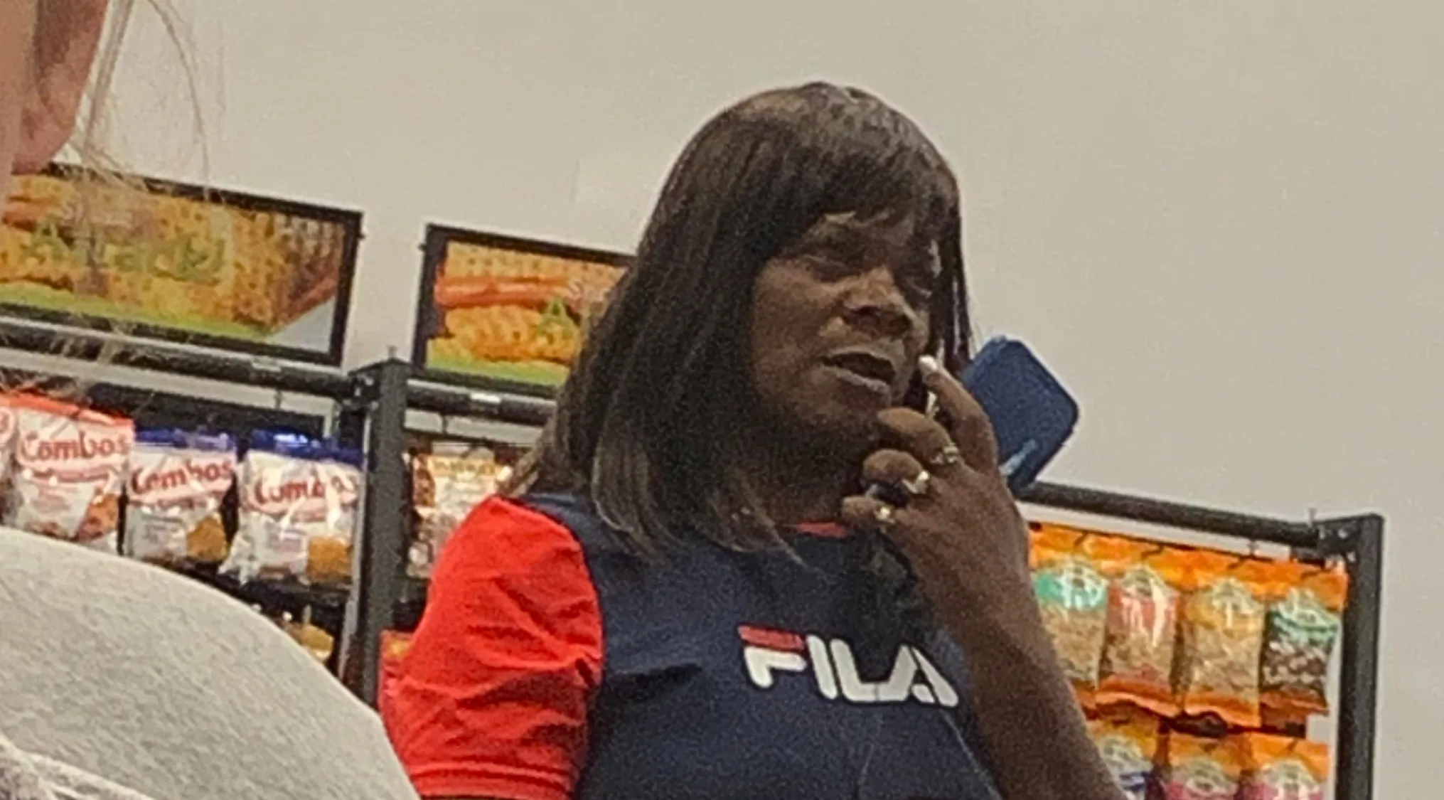 Woman with dark hair and a FILA shirt on the phone. A Celebrity Doppelgangers resemblance is being questioned.