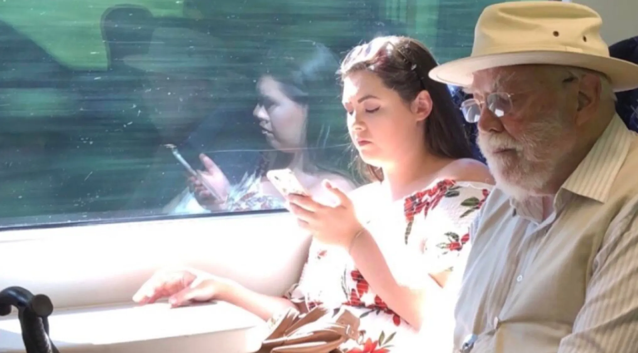 A young woman on her phone next to a man with a white beard and hat. Find celebrity doppelgangers.