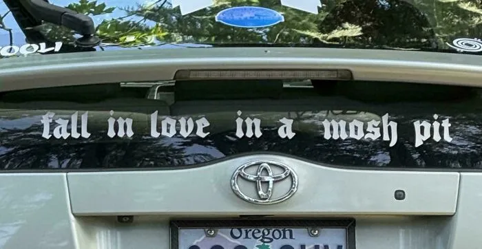 Wild bumper sticker: Fall in love in a mosh pit on the back of a car.