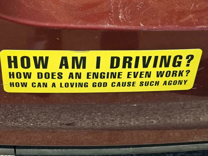 A funny, wild, and unfiltered bumper sticker on a brown car asking: How am I driving? How does an engine even work? How can a loving God cause such agony.