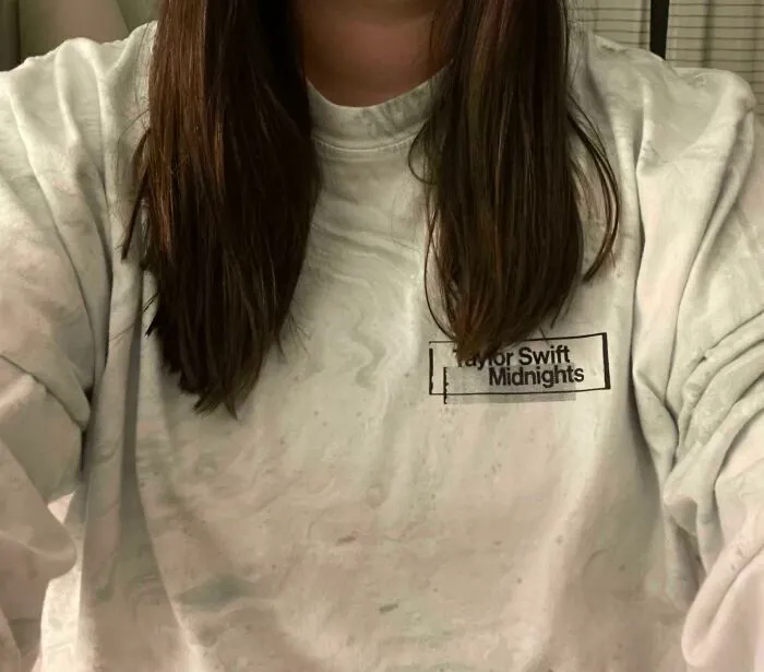 A woman with long dark hair, showing a hair salon disaster where her shirt was stained during the process.