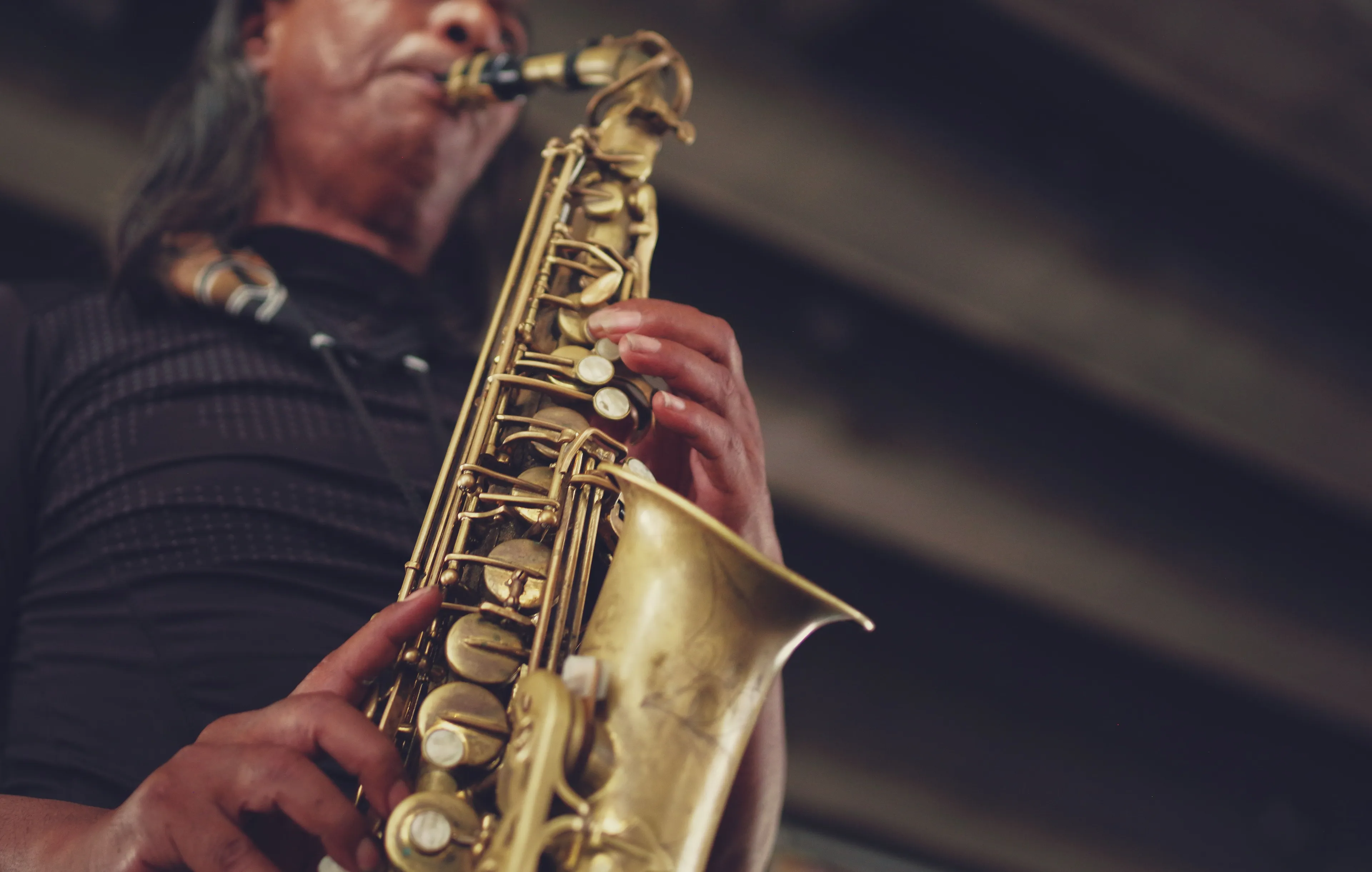 A musician playing a saxophone, showcasing the Art of music. The brass instrument is held by hands pressing keys.