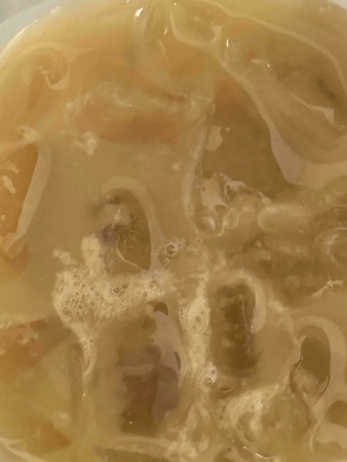 A close-up of a melted drink, likely from a food delivery fail, showing the ice has completely dissolved.
