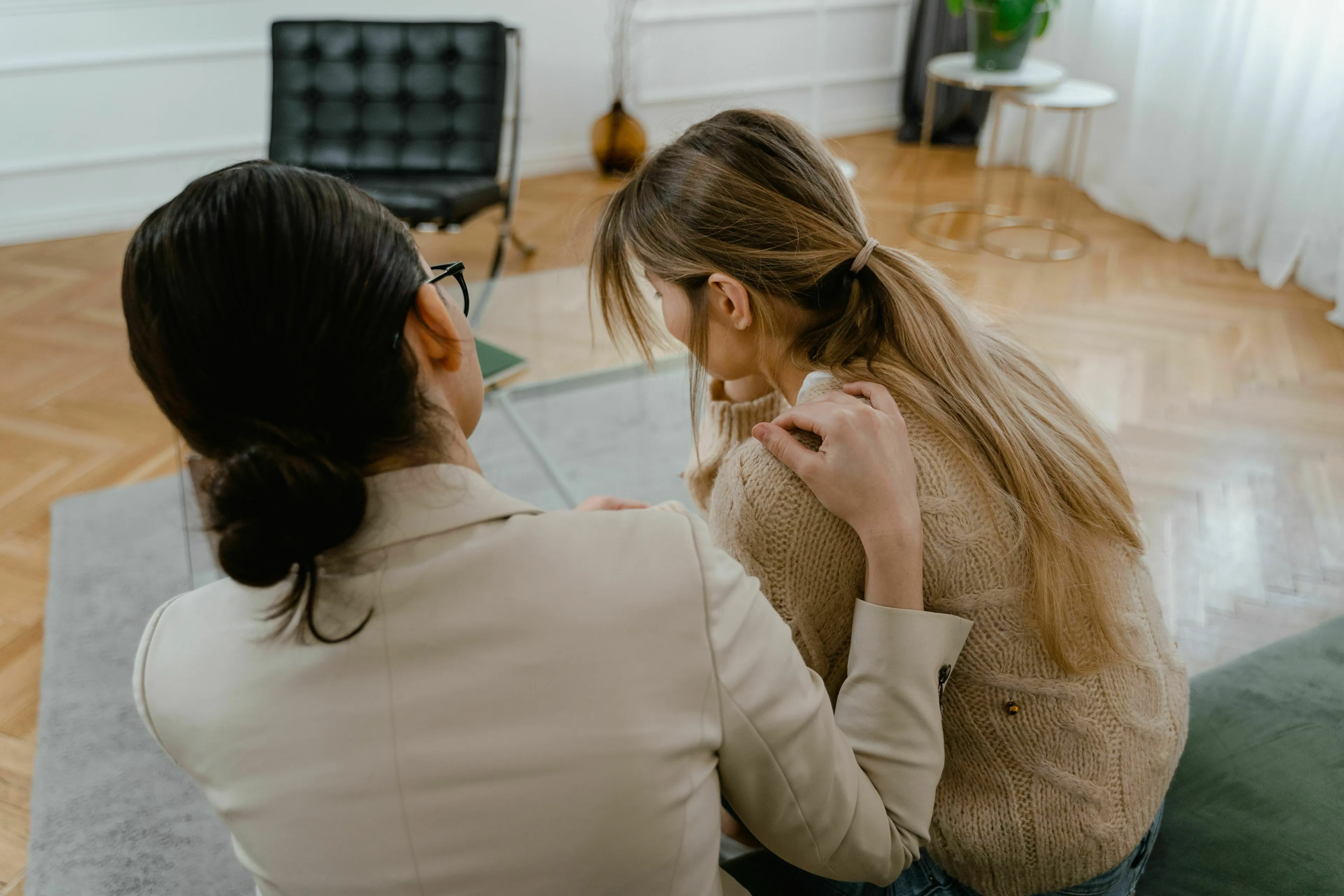 Two women, viewed from behind. One woman comforts the other, who appears distraught. How extroverted are you?