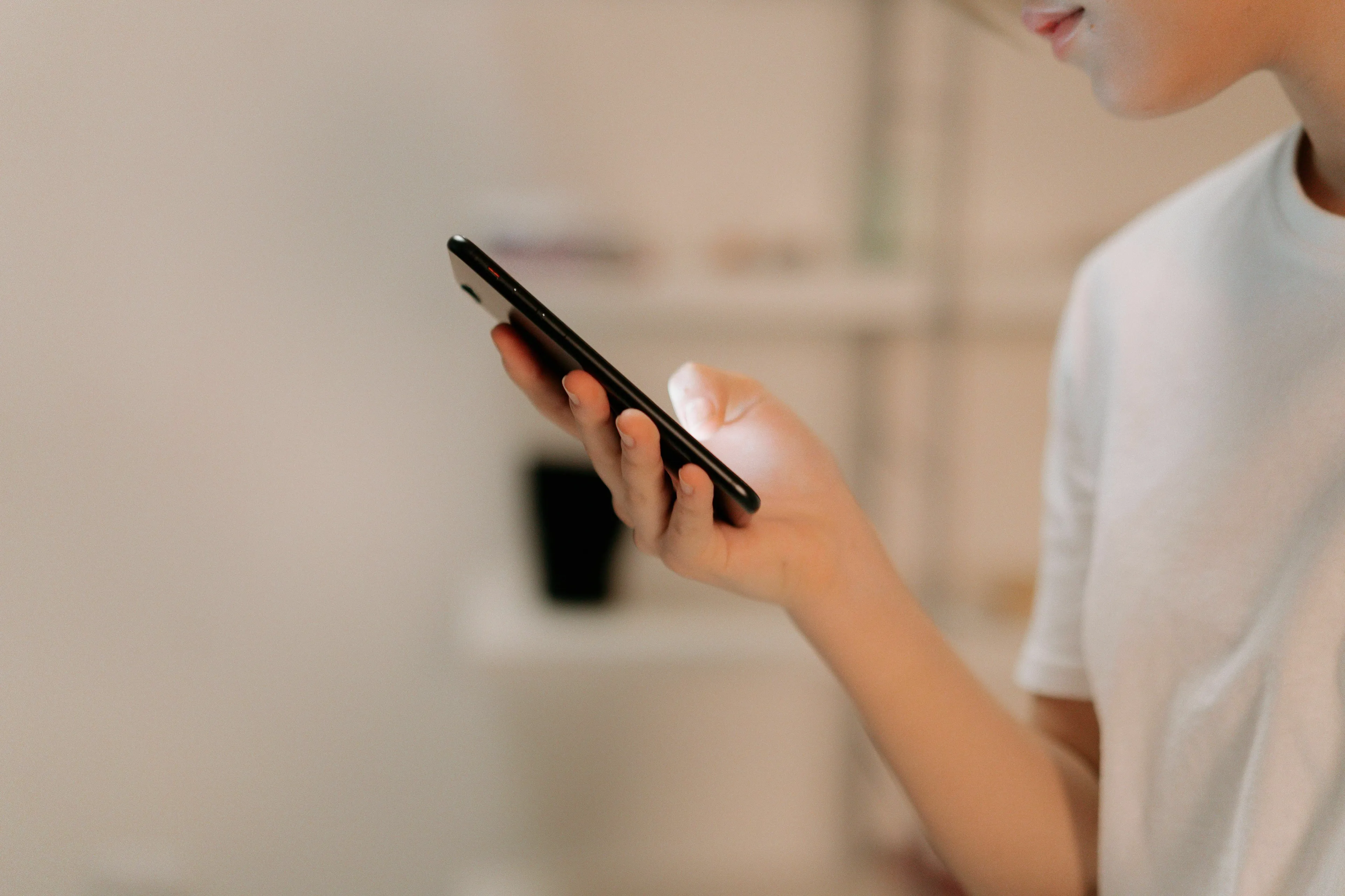 A person in a white shirt holds a black smartphone with a glowing screen. How extroverted are you?