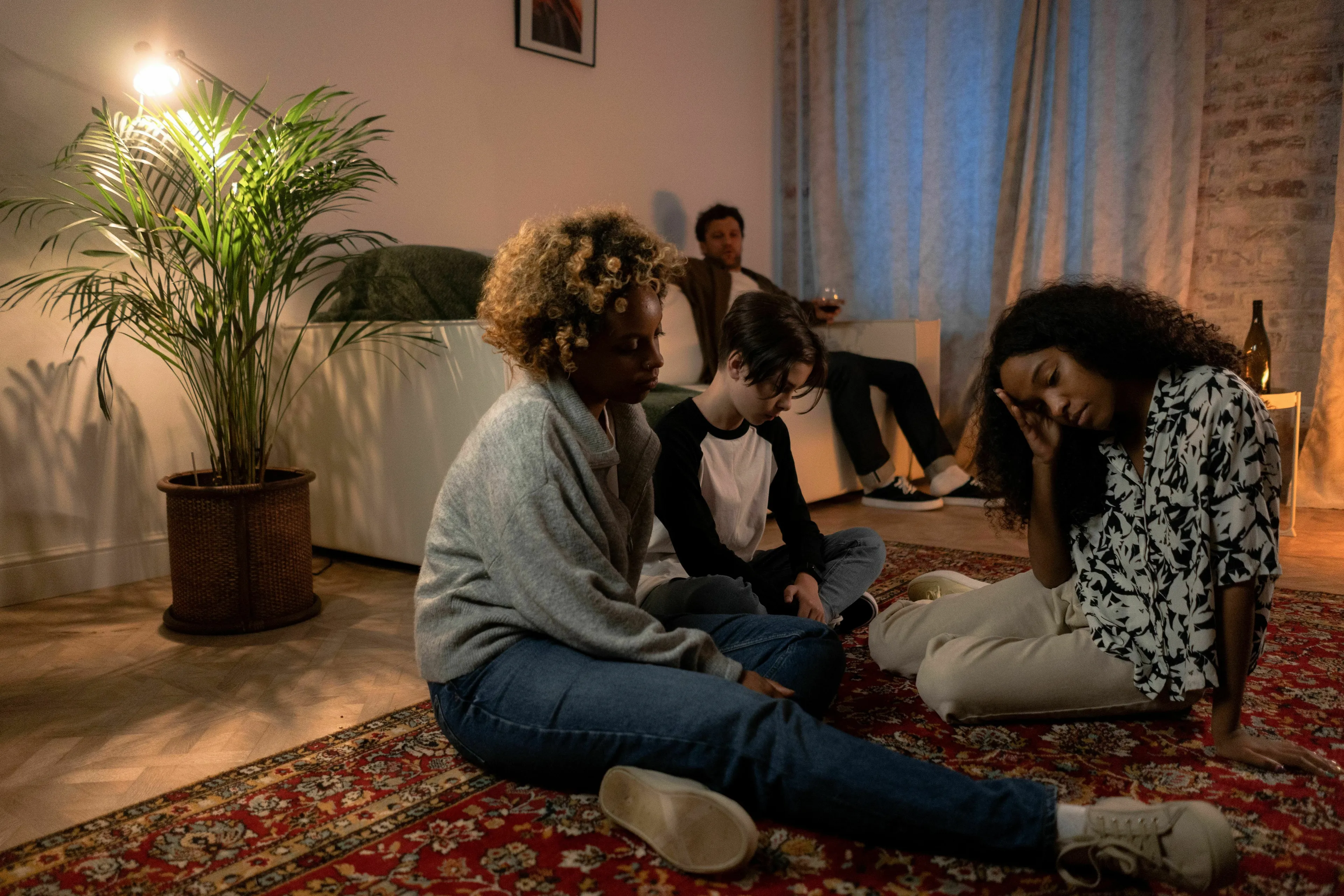Group of friends sitting on a rug, one woman looking down, reflecting how extroverted are you when there's a long silence in a group.
