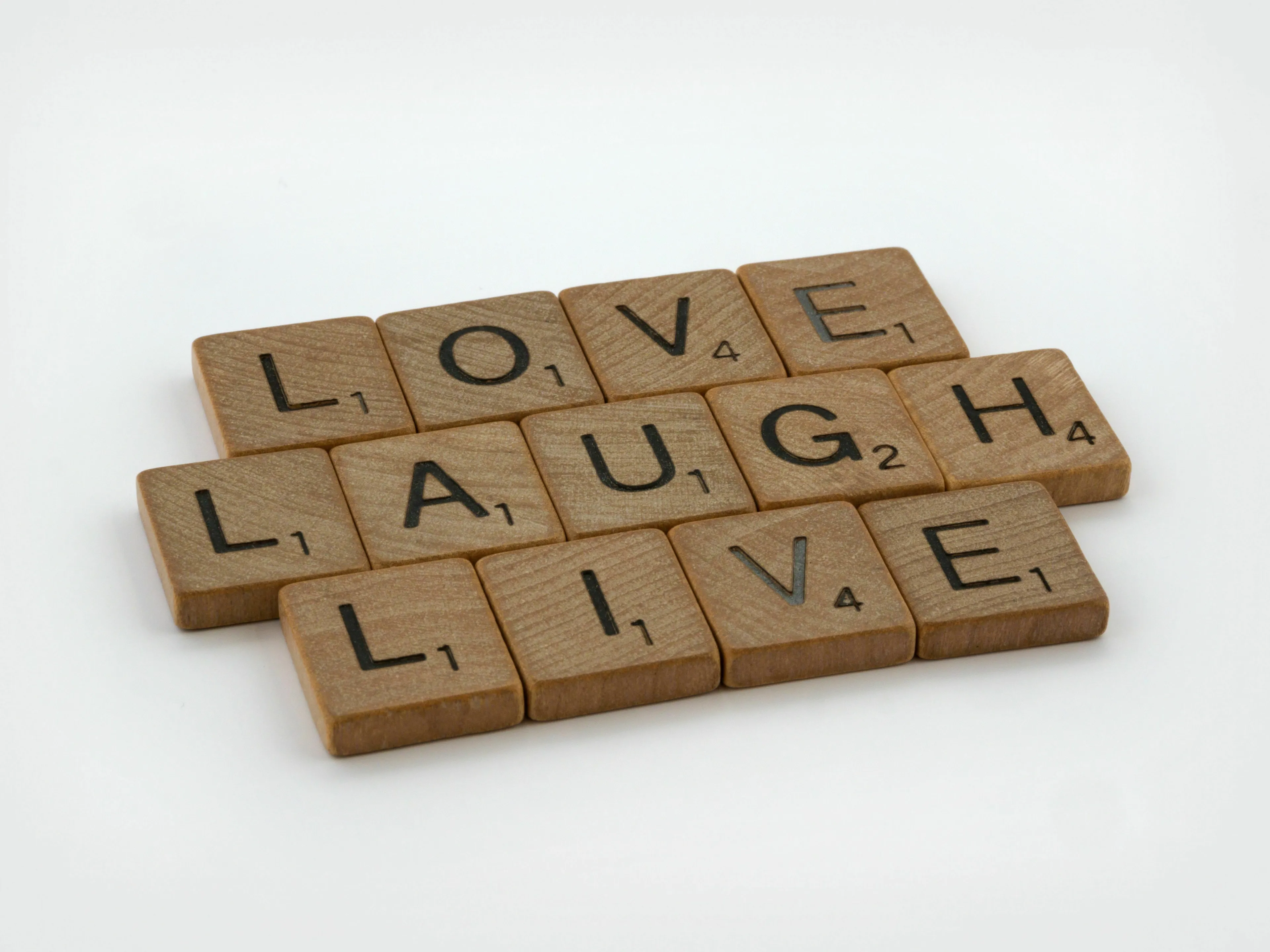 Scrabble tiles spelling LOVE LAUGH LIVE on a white background, representing a proverb you live by, showing your extroverted personality.