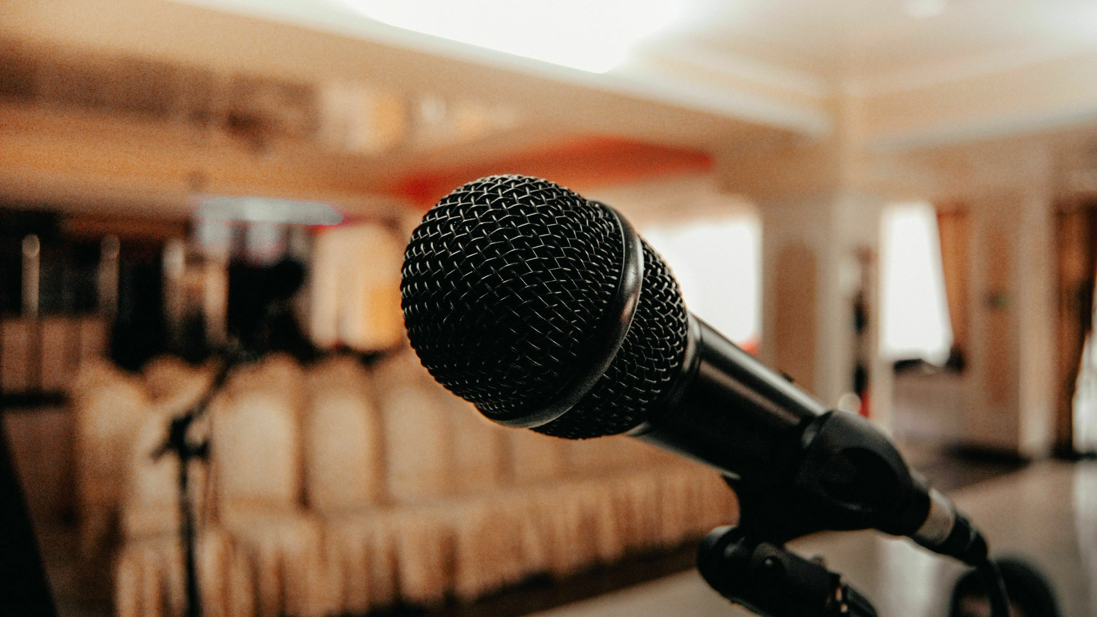 A close-up of a microphone on a stand, with a blurred party or event space in the background. How extroverted are you?