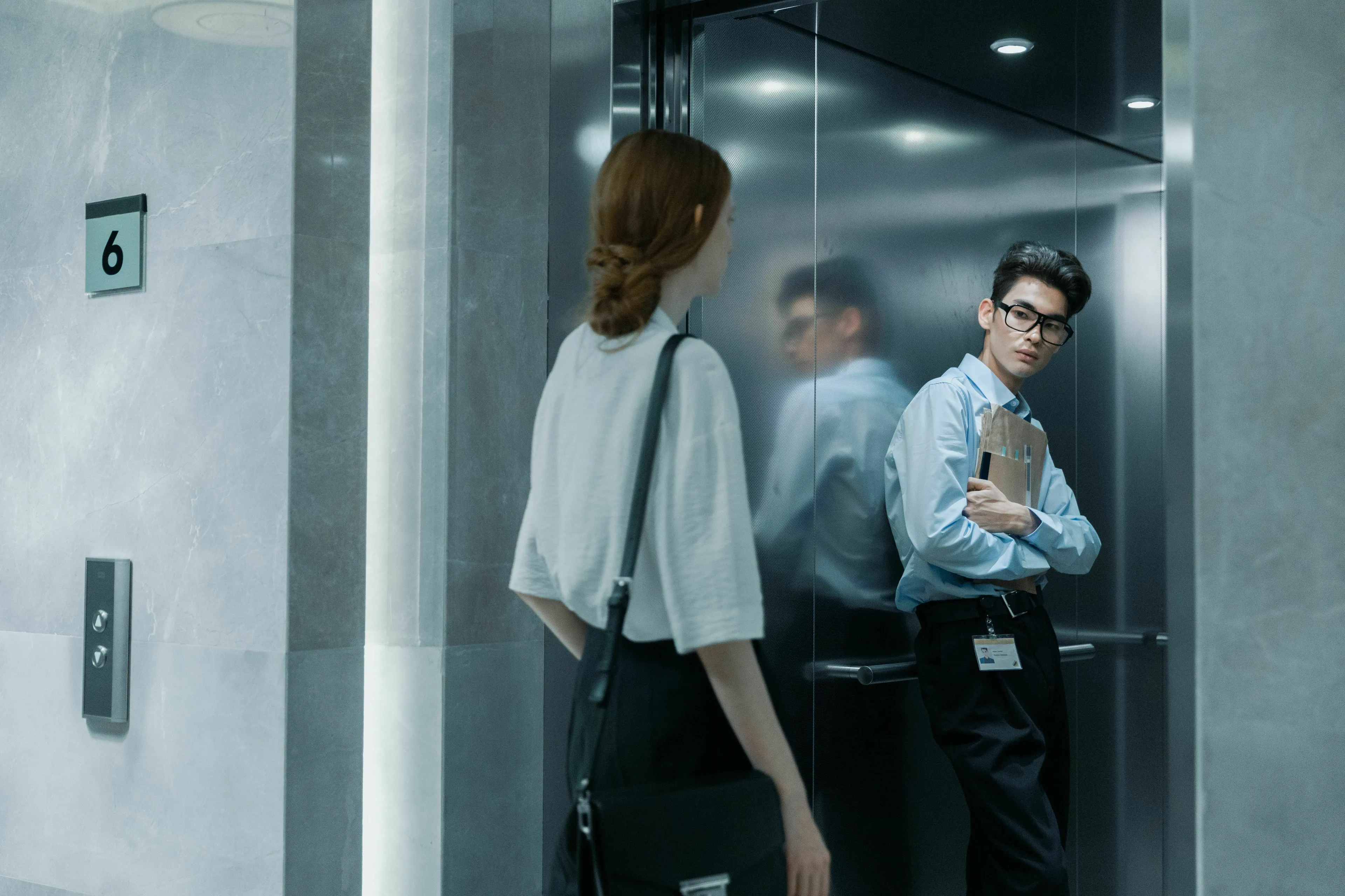 Two people in an elevator, one facing the doors, the other reflected, for an extroverted personality quiz.