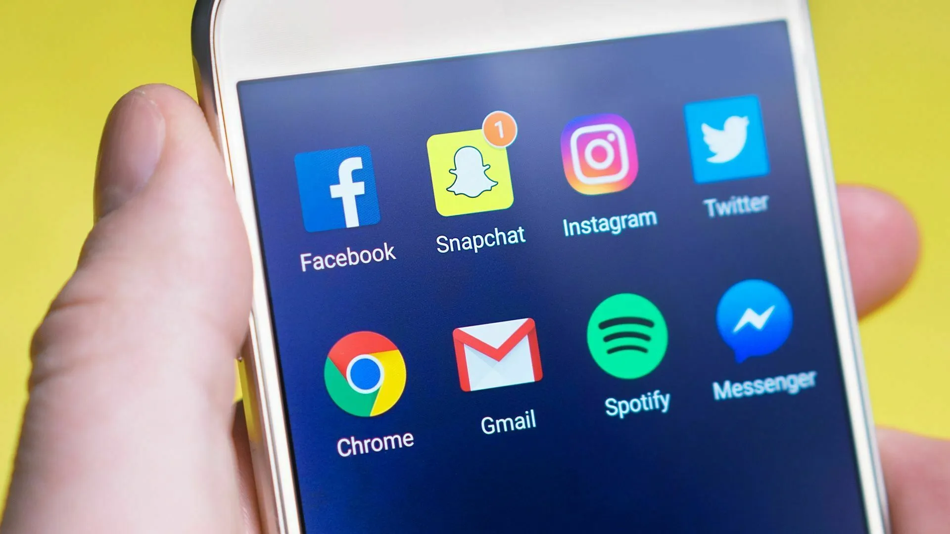 A hand holding a smartphone displaying social media app icons. How extroverted are you and your relationship with social media?