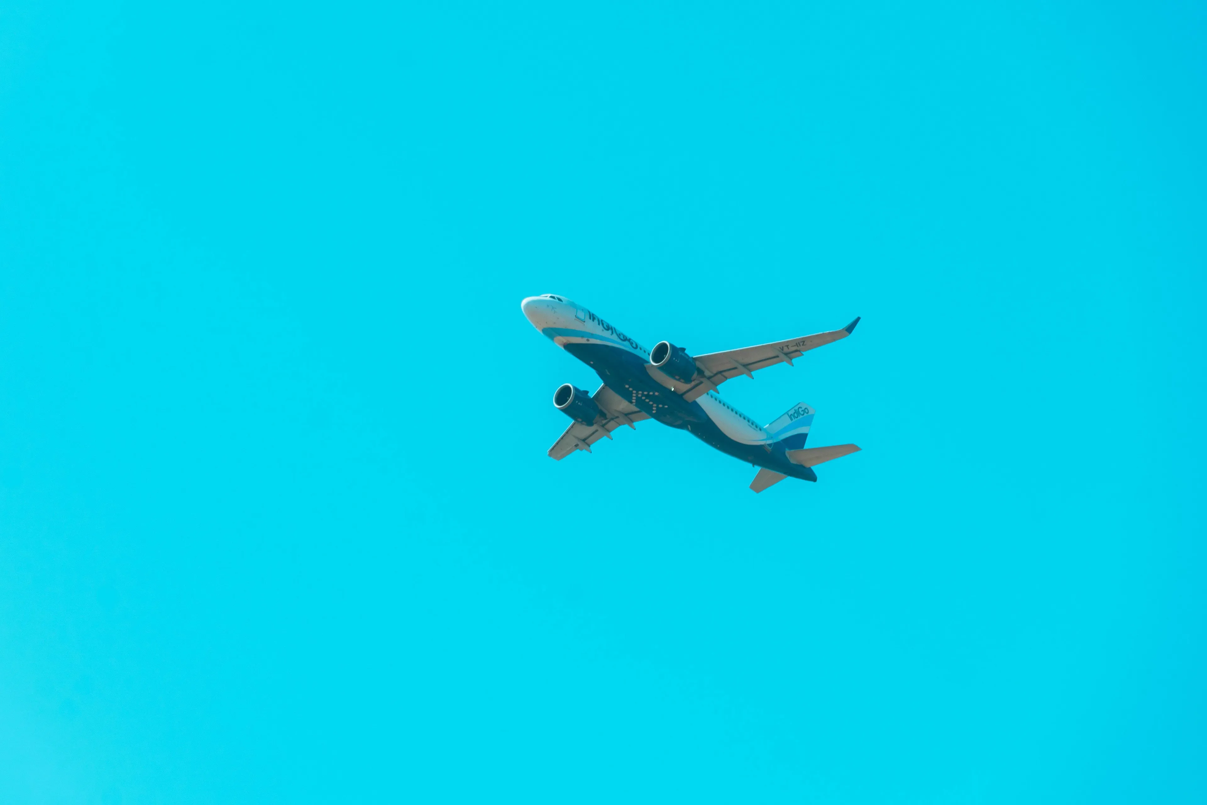 An airplane in flight against a clear blue sky, illustrating topics like how to handle a long flight or being extroverted.