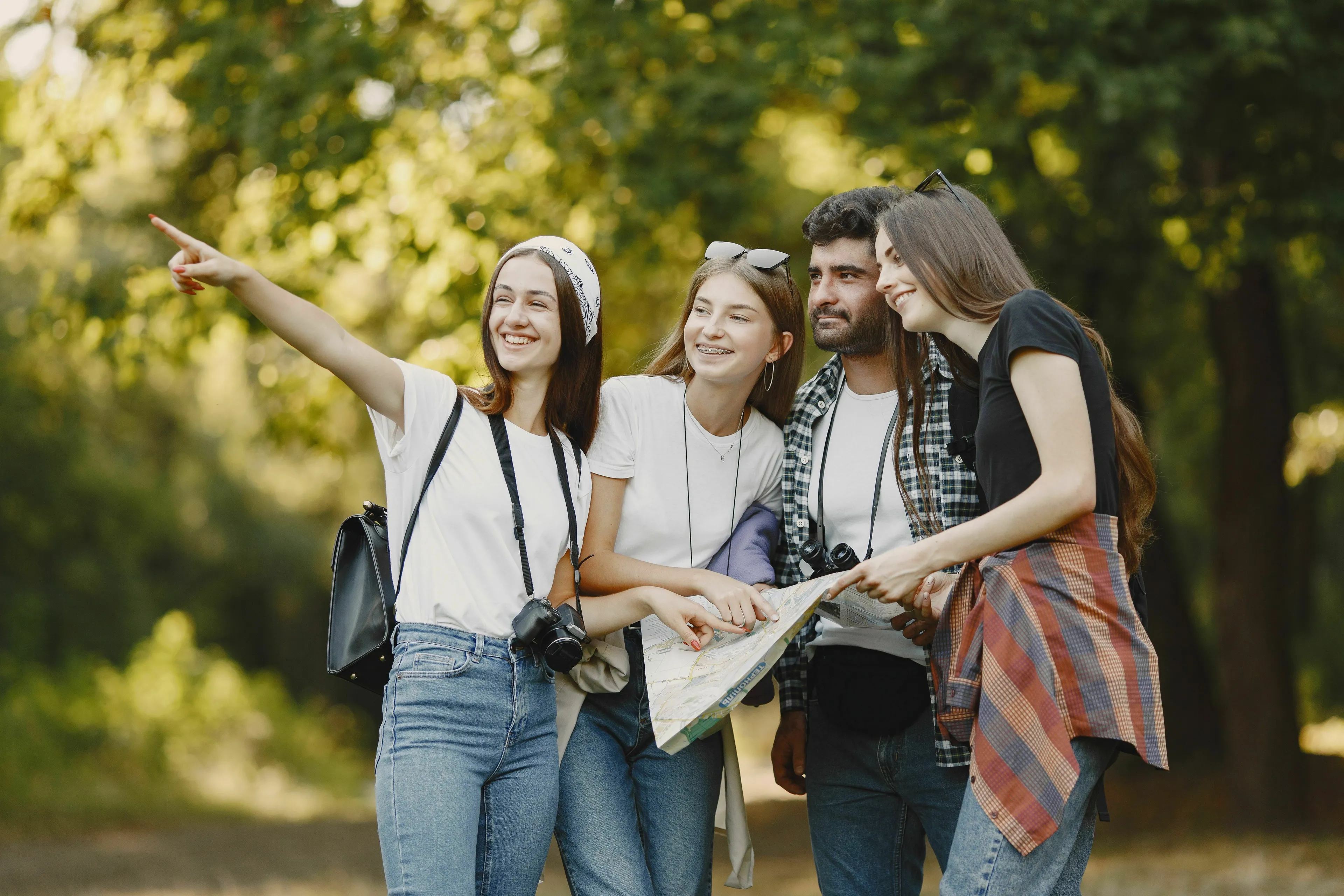 Four smiling friends with a map, one pointing, enjoying a trip. How extroverted are you and who's coming?
