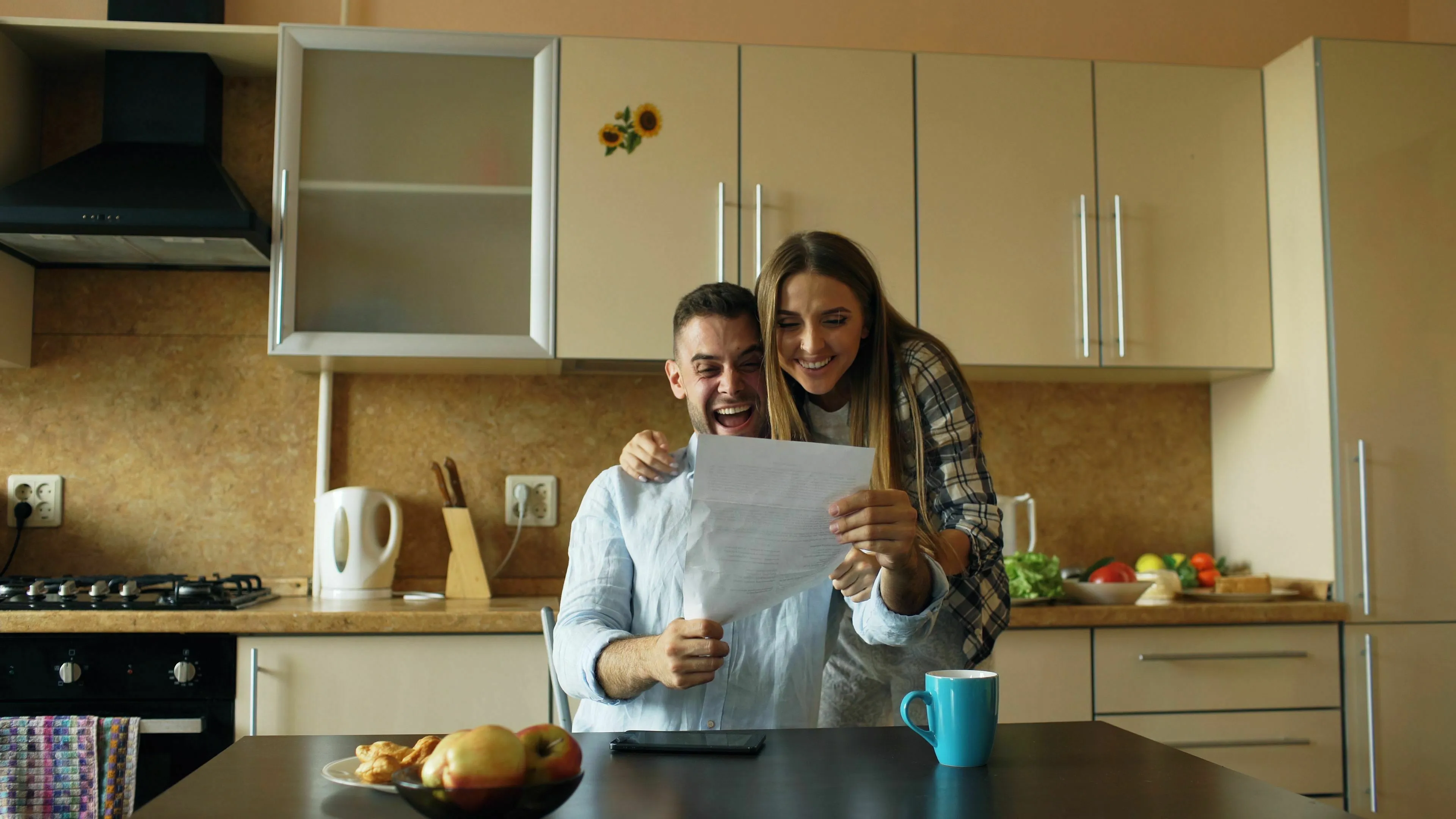 A happy couple in a kitchen, excited about something they are reading. How extroverted are you? How do you share good news?
