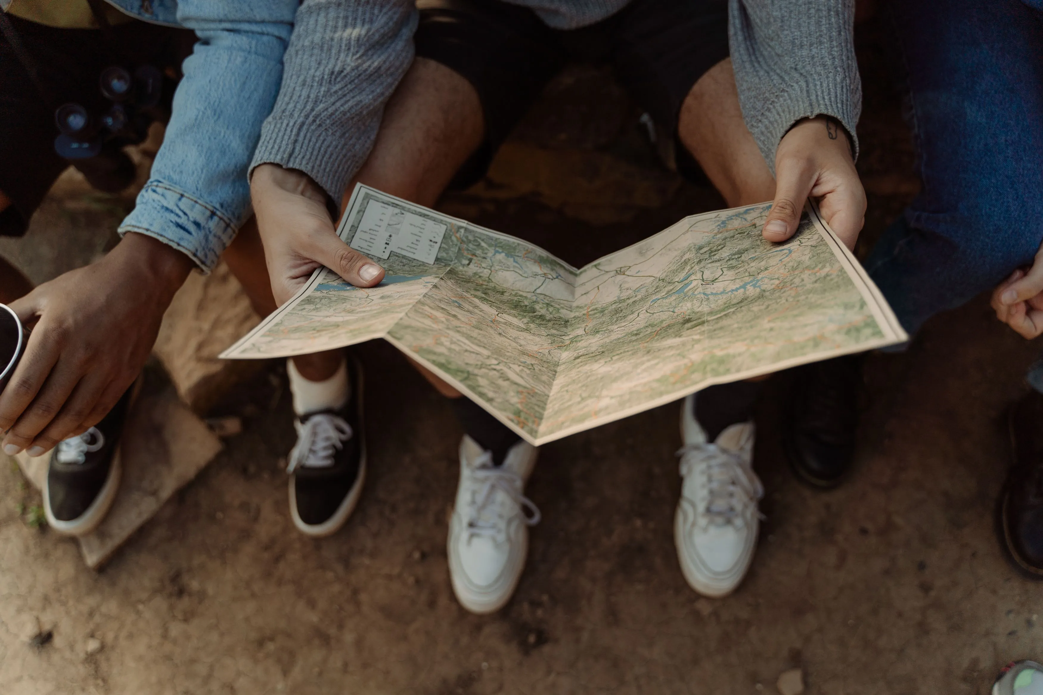 Friends consulting a map together, coordinating a trip and choosing a vacation style.