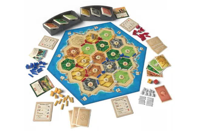 A top-down view of the Catan board game laid out, showing the hexagonal resource tiles, cards, dice, and player pieces.