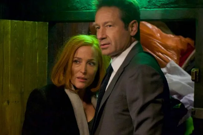 Mulder & Scully, the iconic duo, looking intently with green lighting in an intense scene.