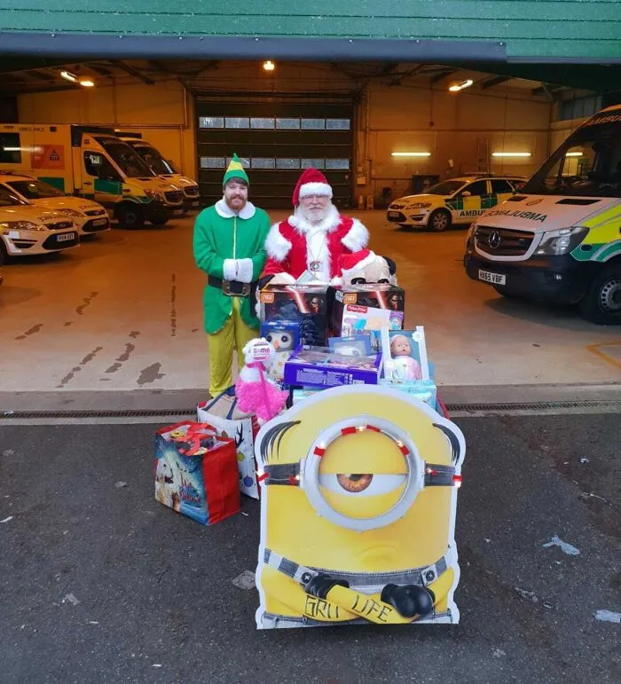 Santa and an elf with a pile of toys, showing the generosity of amazing fathers during the holidays.